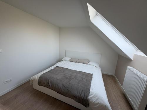 a white bedroom with a bed in a attic at De Boomgaard in Nieuwerkerken