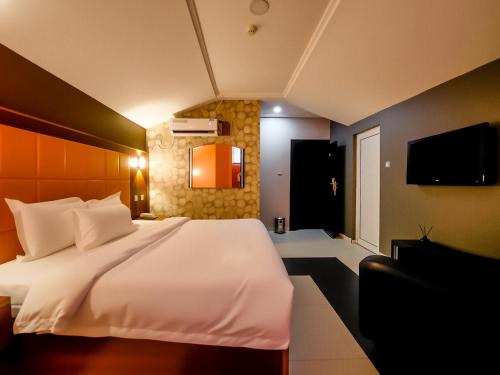 a bedroom with a large white bed and a television at Aotel Hotel Lagos Ago in Lagos