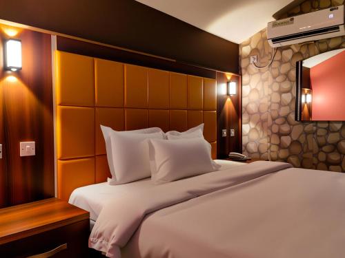 a bedroom with a large bed with white pillows at Aotel Hotel Lagos Ago in Lagos