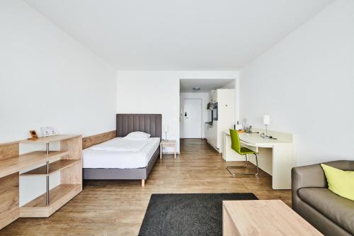 a bedroom with a bed and a desk and a couch at ADAPT APARTMENT HOTEL Giessen in Gießen