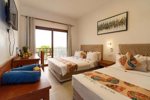 a hotel room with two beds and a balcony at Malika Nungwi Hotel in Nungwi