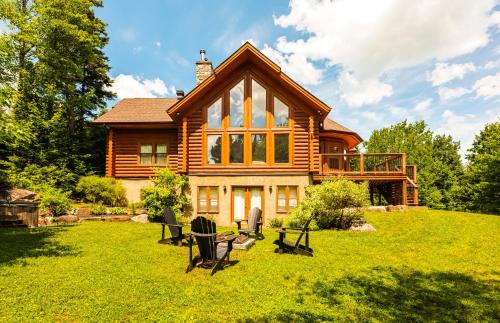 a log house on a hill with chairs in the yard at Fiddler Lake Resort - Deer 59 in Mille-Isles