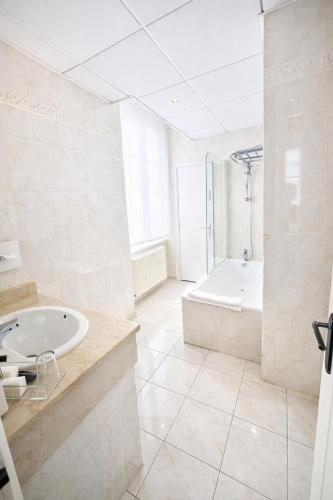 a large white bathroom with a tub and a sink at Le Grand Hôtel de Mayenne - Logis hôtels restaurant in Mayenne