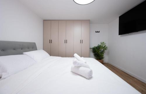 a white bedroom with two beds and a tv at לב המעיין- סוויטה מושלמת עם ג'קוזי במושב פסטורלי in Reẖov