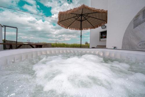 an umbrella in a hot tub with water at לב המעיין- סוויטה מושלמת עם ג'קוזי במושב פסטורלי in Reẖov