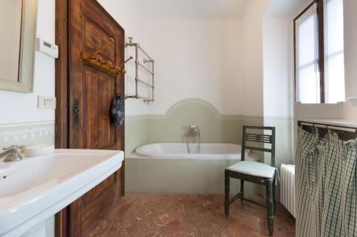 a bathroom with a tub and a sink and a chair at Palazzo Guicciardi in San Bernardo