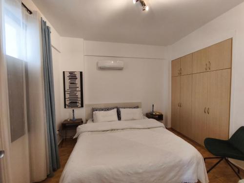 a bedroom with a large white bed and a chair at Queens gardens in Paphos