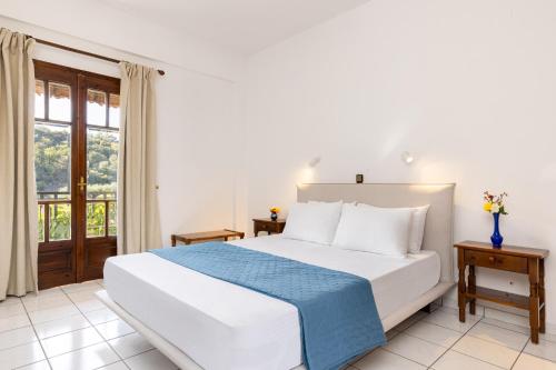 a bedroom with a white bed and a window at Lagos House Α in Kámpos