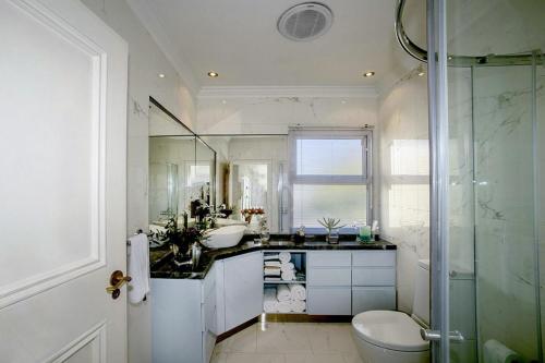 a bathroom with a sink and a toilet and a shower at The Seaside View in Simonʼs Town