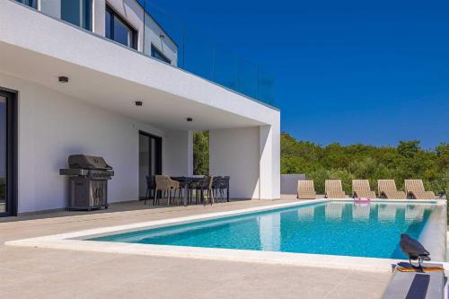 ein Schwimmbad mit Tisch und Stühlen neben einem Gebäude in der Unterkunft Villa ELEVATION in Vrh
