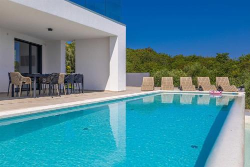 ein Swimmingpool mit Stühlen und einem Tisch neben einem Haus in der Unterkunft Villa ELEVATION in Vrh