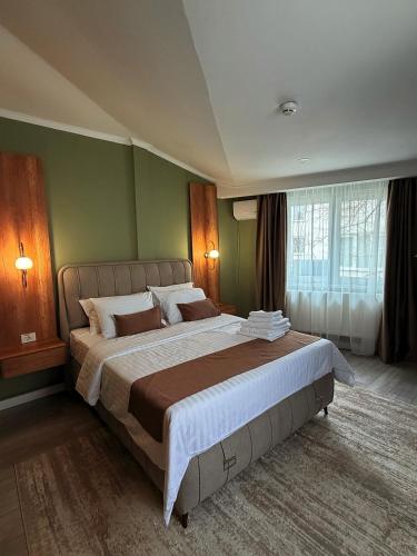a large bed in a bedroom with green walls at Sawei Urban Hotel in Craiova