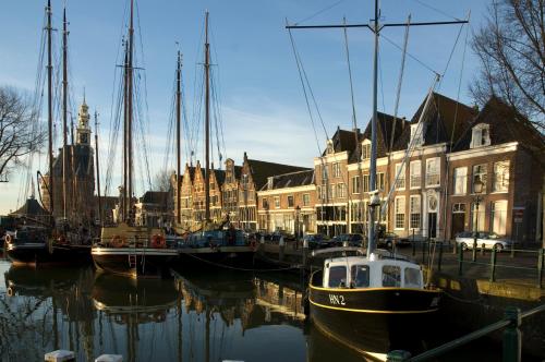 a boat is docked in a marina with houses at Hotelhuisjes Medemblik in Wieringerwerf