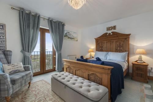 a bedroom with a large bed and a chair at Bay View - holiday cottage by the sea with stunning views in Pendine