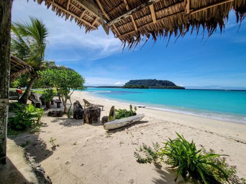 a beach with a boat sitting on the sand at Port Olry BBQ Table and Camping Side in Port-Olry