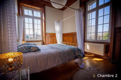 a bedroom with a bed in a room with windows at Gite Logis des Fontaines in Raon-lʼÉtape
