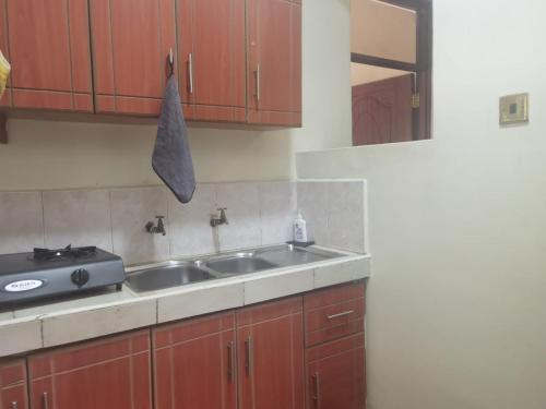 a kitchen with a sink and wooden cabinets at Kismet Hideaway in Nairobi