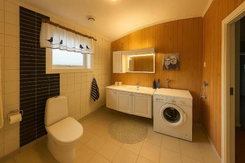 a bathroom with a toilet and a washing machine at Guesthouse in Hellosan in Vestvågøya