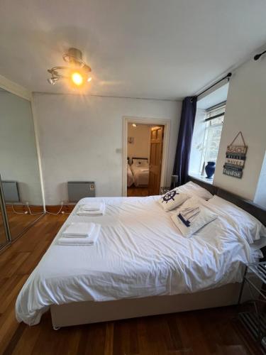 a bedroom with a bed with white sheets and a window at Apartment Porthmadog harbourside fantastic estuary views Great spot with parking in Porthmadog