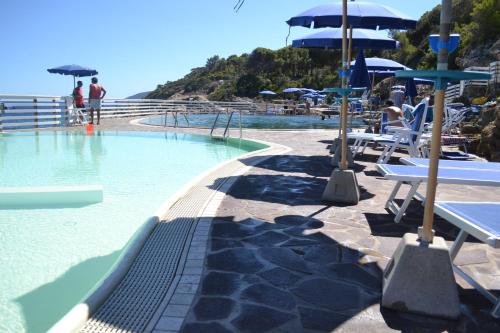 a swimming pool with tables and umbrellas next to the ocean at Magic View in Tuscany in Capo D'Arco