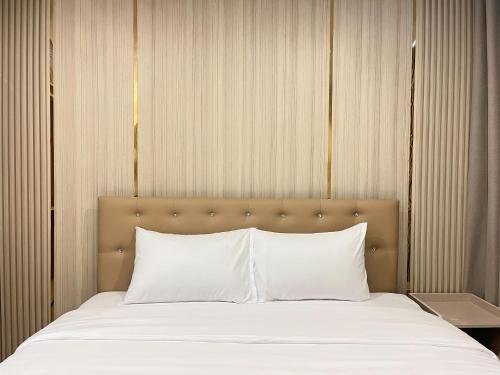 a bed with white pillows in a room at DF Hotel Pattaya in Pattaya South