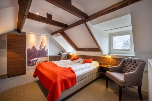 a attic bedroom with a bed and a chair at Hotel Bergrust in Bemelen