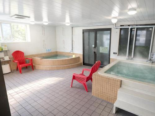 a large bathroom with a hot tub and red chairs at A-GATE Hotel Hakodate in Hakodate