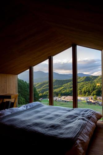 a bed in a room with a large window at Earthboat Minakami Hodaigi in Minakami