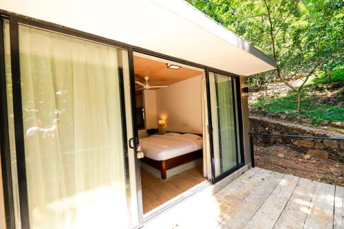 a room with a bed and a sliding glass door at Dilco Nature Resort - BERAGALA in Dambawelagama