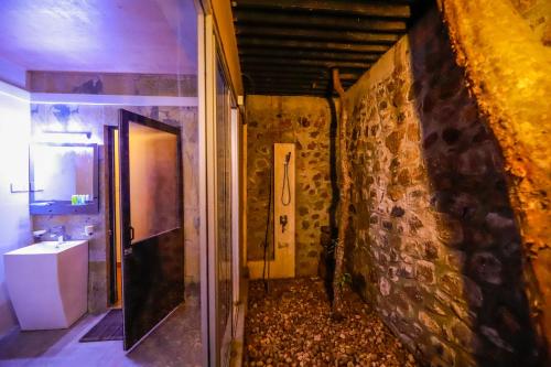 a bathroom with a sink and a stone wall at Dilco Nature Resort - BERAGALA in Dambawelagama