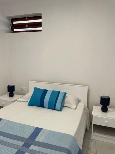 a bedroom with a bed with blue and white pillows at Apartamentos Andrade in Espargos