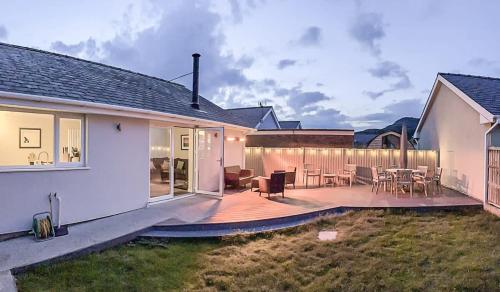 a house with a deck with tables and chairs at Family-Friendly Retreat between Beach & Mountains in Tremadoc