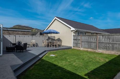 a backyard with a deck with a table and an umbrella at Family-Friendly Retreat between Beach & Mountains in Tremadoc