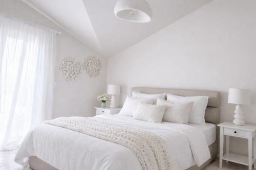 a white bedroom with a white bed with white pillows at Valeria's Apartment in Argostoli