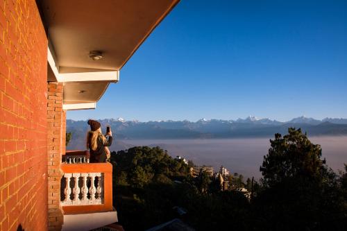 a person standing on a balcony looking out at the water at Peaceful Cottage & Cafe Du Mont in Nagarkot