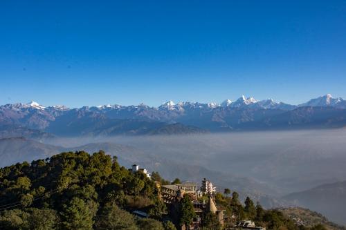 a house on a hill with mountains in the background at Peaceful Cottage & Cafe Du Mont in Nagarkot