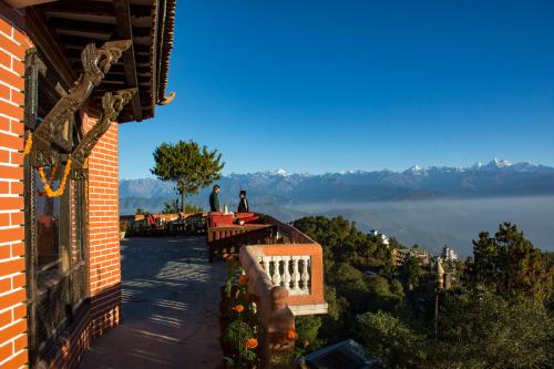 two people standing on a balcony of a building with a view of the water at Peaceful Cottage & Cafe Du Mont in Nagarkot