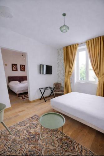 a living room with a white bed and a glass table at Hotel La Baie Royale in Pontorson