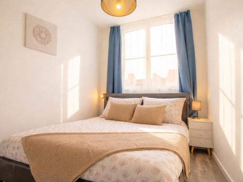 a bedroom with a bed with blue curtains and a window at Appartement Centre Saint-Omer, Parking privé gratuit in Saint-Omer