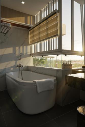a white bath tub in a bathroom with a window at Cát Tường Hotel in Da Lat