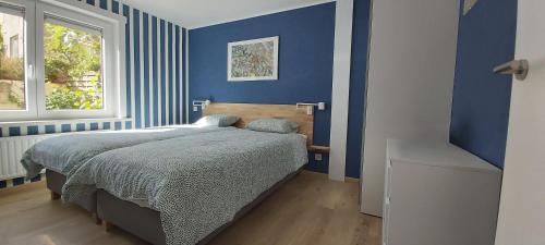 a blue bedroom with a bed and a window at Seagarden by Valdemosa in De Haan