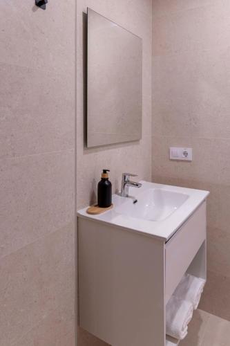 a white bathroom with a sink and a mirror at Apartamentos Armonia Peñíscola in Peniscola