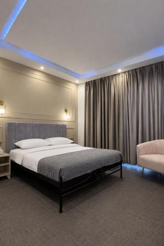 a bedroom with a large bed and a chair at NOHO Boutique Koukaki , premium living in Athens