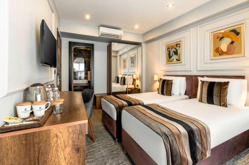 a hotel room with two beds and a desk at Zalel Hotels Laleli in Istanbul
