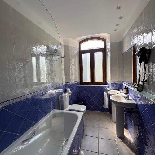 a blue tiled bathroom with a tub and a sink at Aguas de Ibias in Cecos