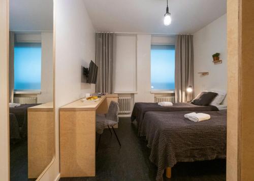 a hotel room with two beds and a desk at Forenom Hostel Jyväskylä in Jyväskylä