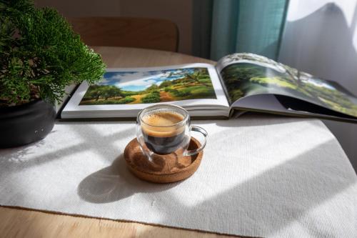a cup of coffee on a table next to a book at Casa do Lado, Flores Açores in Lajes das Flores