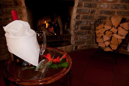 een tafel met een wijnglas en een open haard bij De Ark Mountain Lodge in Clarens