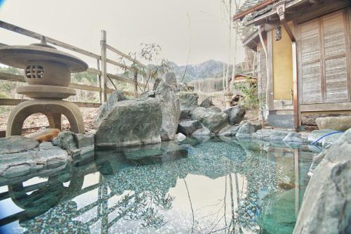 a pool of water in front of a house at 24時間源泉かけ流しを ひとりじめできる 一棟貸しVilla安曇野 in Azumino