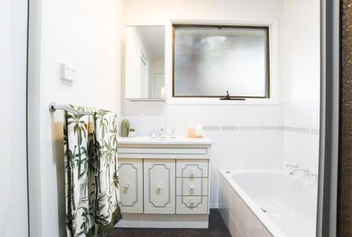a bathroom with a tub and a sink and a window at The Salt Shack in Mallacoota